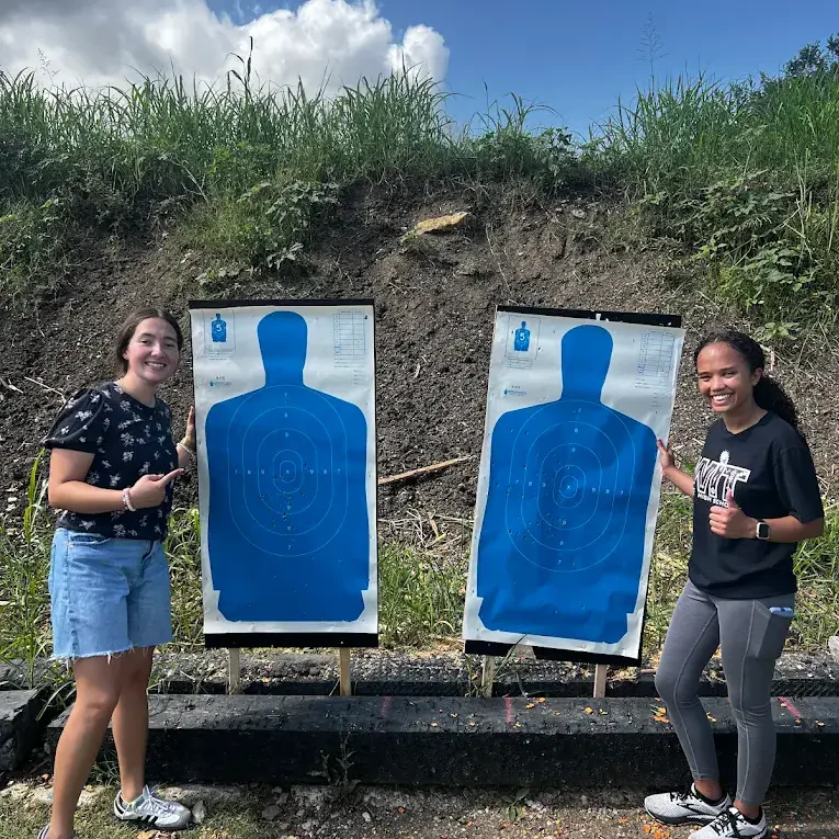 Target shooting training at Big Iron Handgun License Course in Waco, with two smiling women posing confidently.